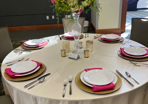 Round banquet tables with white linens and place settings